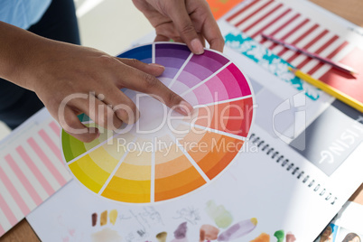 Graphic designer holding color swatch at desk