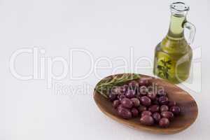 High angle view of brown olives in plate by oil in jar