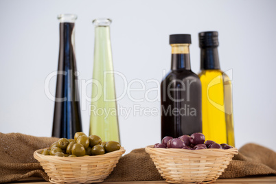 Olives in wicker basket with oil bottle