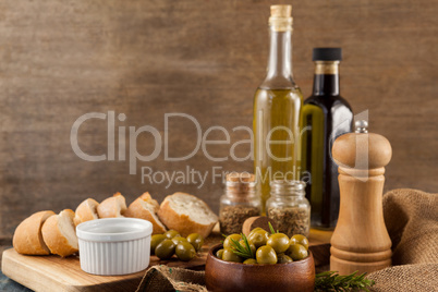 Olives with pepper shaker and oil bottles by bread