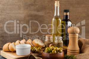 Olives with pepper shaker and oil bottles by bread