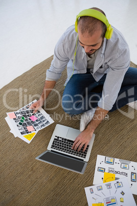 High angle view of designer with collage using laptop while sitting on floor