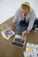 High angle view of designer with collage using laptop while sitting on floor