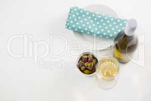 Overhead of marinated olives with glass and bottle of wine