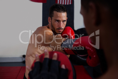 Trainer assisting man in boxing