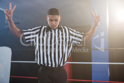 Young male referee gesturing while looking down in boxing ring