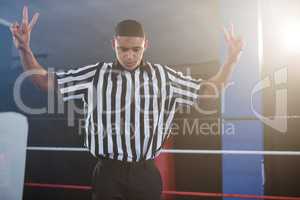Young male referee gesturing while looking down in boxing ring