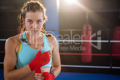 Portrait of young female athlete wrapping red bandage on hand
