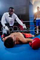 Male boxer looking while referee counting by athlete