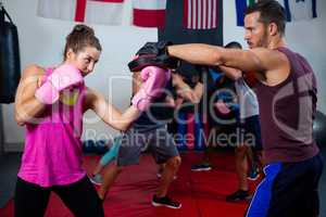 Female boxer and instructor practicing with boxing