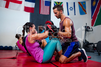 Male instructor assisting female boxer