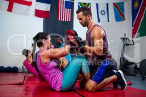 Male instructor assisting female boxer