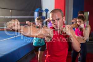 Portrait of young athlete punching by boxing ring