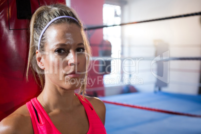 Close-up portrait of young female athlete against boxing ring