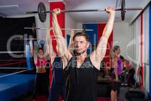 Young athletes lifting barbells with arms raised