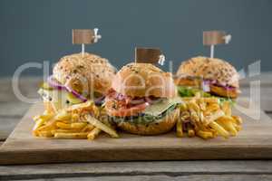Burgers with french fries served on cutting board