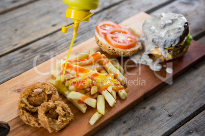 Close up of bottle pouring sauce on French fries