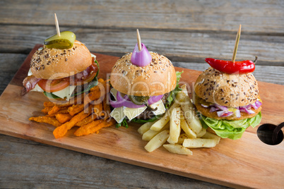Various burgers on cutting board