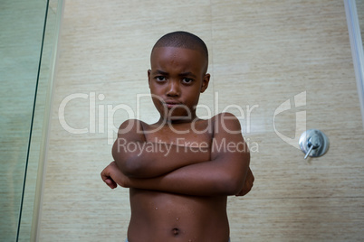 Low angle portrait of shirtless boy with arms crossed at bathroom