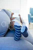 Boy using digital tablet while lying on sofa at home