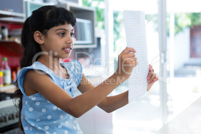 Girl reading paper in kitchen