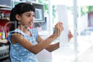 Girl reading paper in kitchen