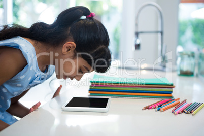 Side view of girl looking at digital tablet on counter