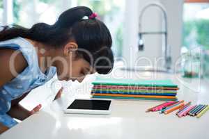 Side view of girl looking at digital tablet on counter