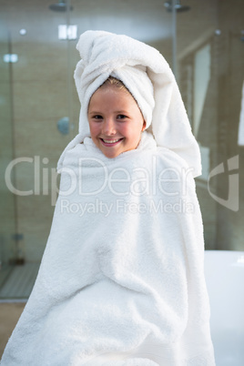 Portrait of cheerful girl wrapped in towel sitting on bathtub