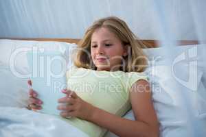 Girl using tablet while lying on bed