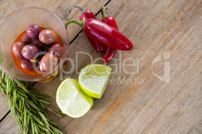 Pickled olives, rosemary with lemon and red chilies on table