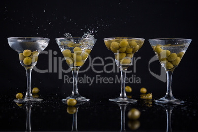 Olives splashing in to a cocktail martini with lime on table