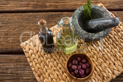 Marinated olives in bowl and rosemary herb on bamboo mat