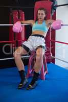 Portrait of tired female boxer sitting on stool at corner