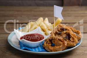 Onion ring and french fries with ketchup arranged in plate