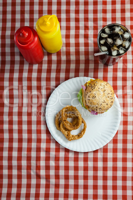 Hamburger, french fries, onion ring and cold drink on napkin