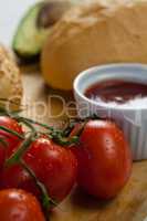 Buns, cherry tomato, sauce on chopping board