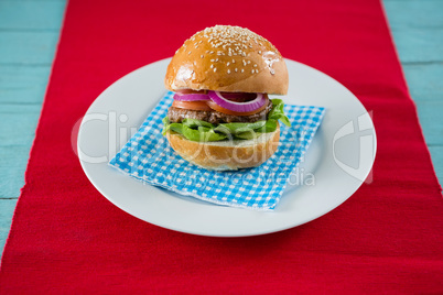 Close up of hamburger served on napkin in plate