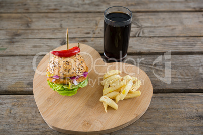 Burger with French fries on heart shape cutting board by drink