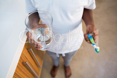 Low section of boy holding brush and glass with water