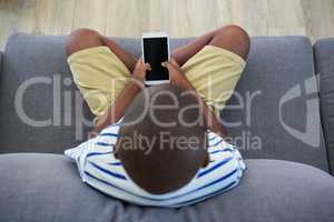 Overhead view of boy using mobile phone on sofa