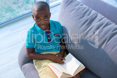 High angle portrait of boy sitting with boy on sofa at home