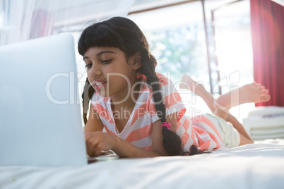 Tilt shot of girl typing laptop on bed