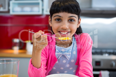 Girl holding breakfast cereal in spoon at home