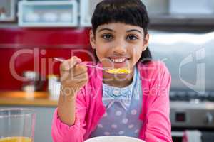 Girl holding breakfast cereal in spoon at home