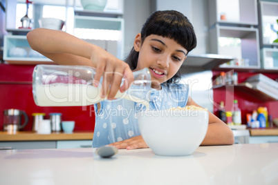 Girl pouring milk in breakfast bowl