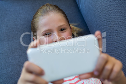 Overhead view of girl using phone while lying on sofa