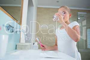 Girl drinking water while holding toothbrush