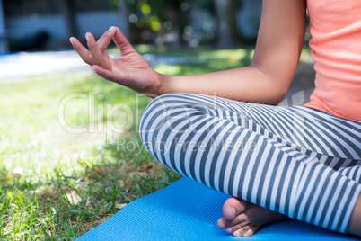 Cropped image of girl meditating in yard