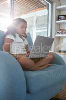 Girl using laptop while sitting on armchair